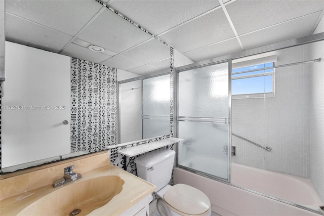 bathroom with a paneled ceiling, shower / bath combination with glass door, vanity, and toilet