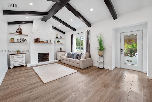 unfurnished living room featuring a brick fireplace, vaulted ceiling with beams, and light wood-type flooring