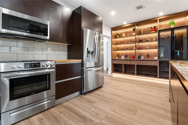 kitchen with tasteful backsplash, stainless steel appliances, butcher block countertops, and light wood-type flooring