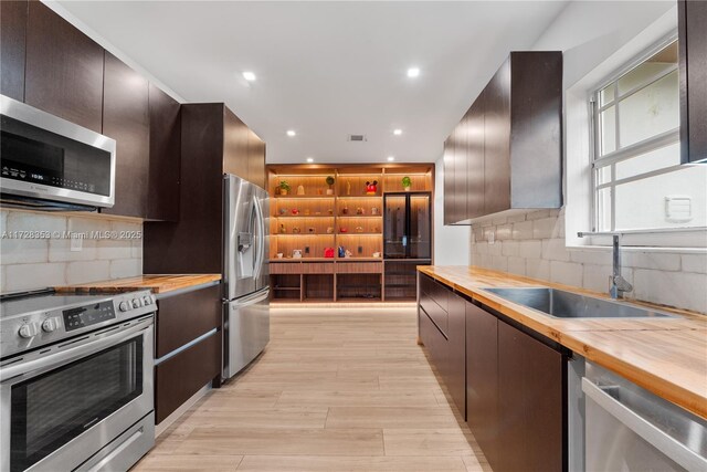 kitchen featuring tasteful backsplash, sink, stainless steel appliances, and wood counters