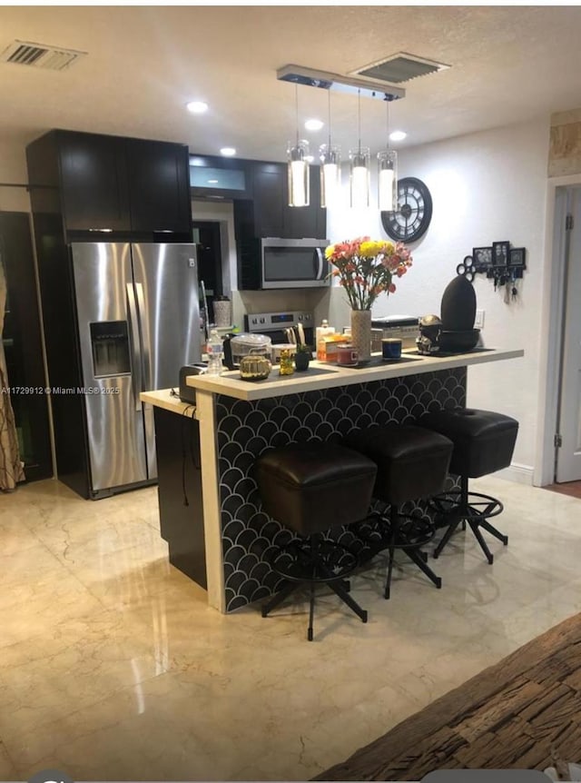 kitchen with stainless steel appliances, hanging light fixtures, and a kitchen breakfast bar