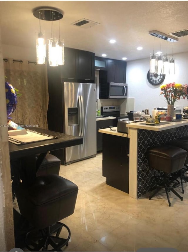 kitchen with pendant lighting, stainless steel appliances, and a kitchen breakfast bar