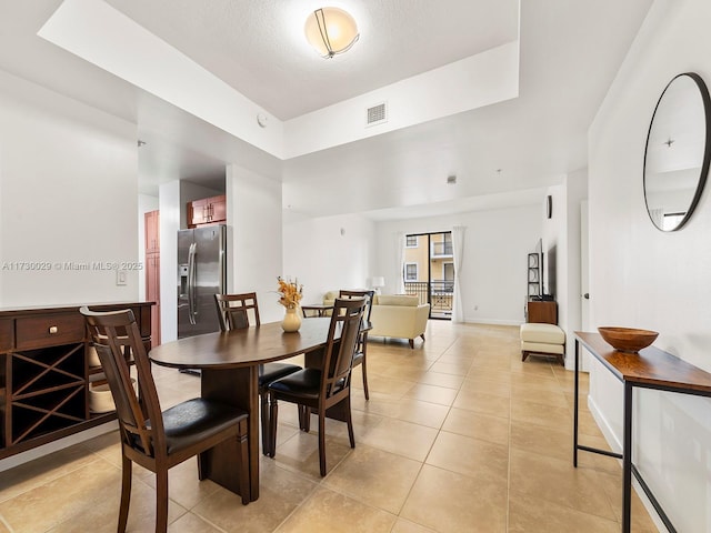 tiled dining room featuring a raised ceiling