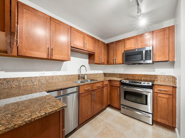 kitchen with sink, stainless steel appliances, stone counters, and rail lighting