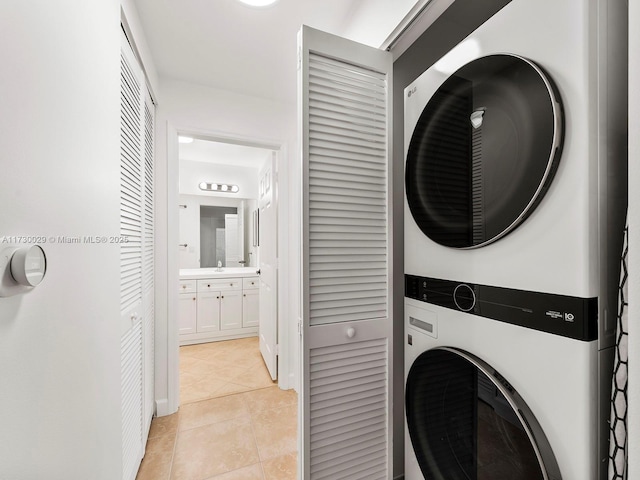 washroom with stacked washer / drying machine and light tile patterned flooring