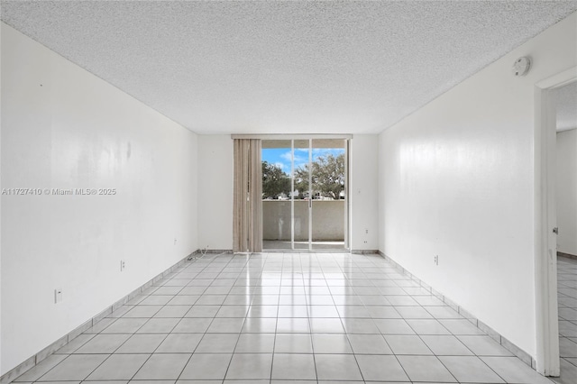 empty room with expansive windows, light tile patterned flooring, and a textured ceiling