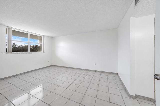 tiled empty room featuring a textured ceiling