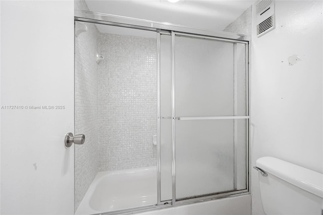 bathroom featuring bath / shower combo with glass door and toilet