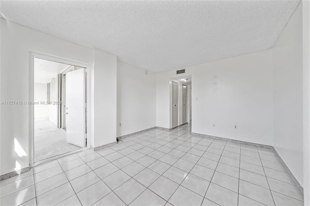 tiled empty room with a textured ceiling