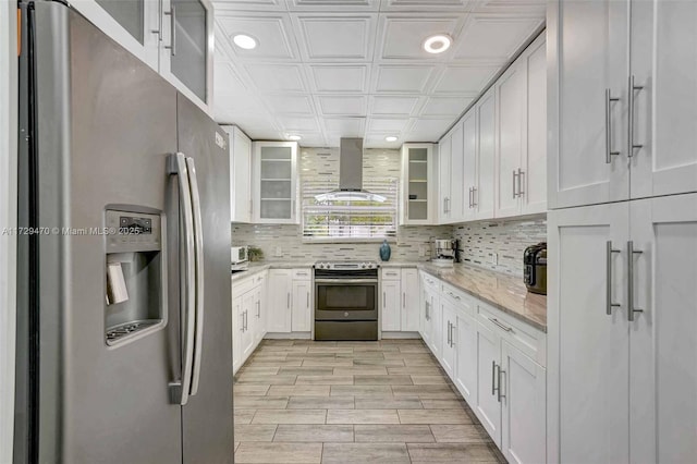 kitchen with white cabinets, stainless steel appliances, extractor fan, and backsplash