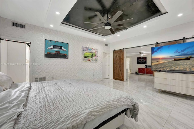 bedroom featuring ceiling fan, a tray ceiling, and a barn door