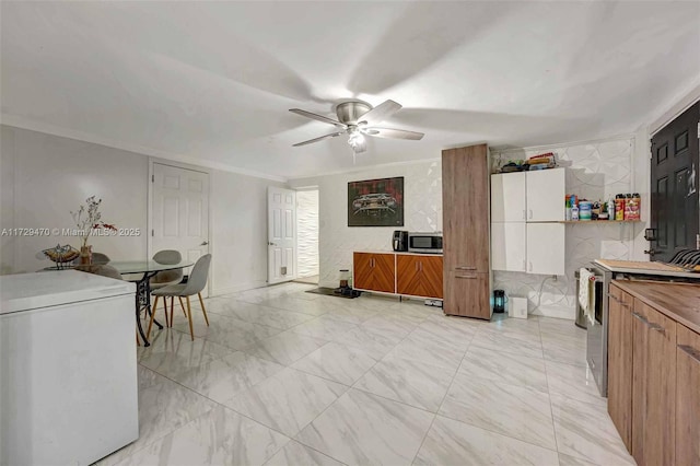 kitchen featuring white cabinets, range, refrigerator, ornamental molding, and ceiling fan