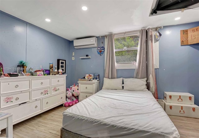 bedroom with light hardwood / wood-style flooring and a wall unit AC