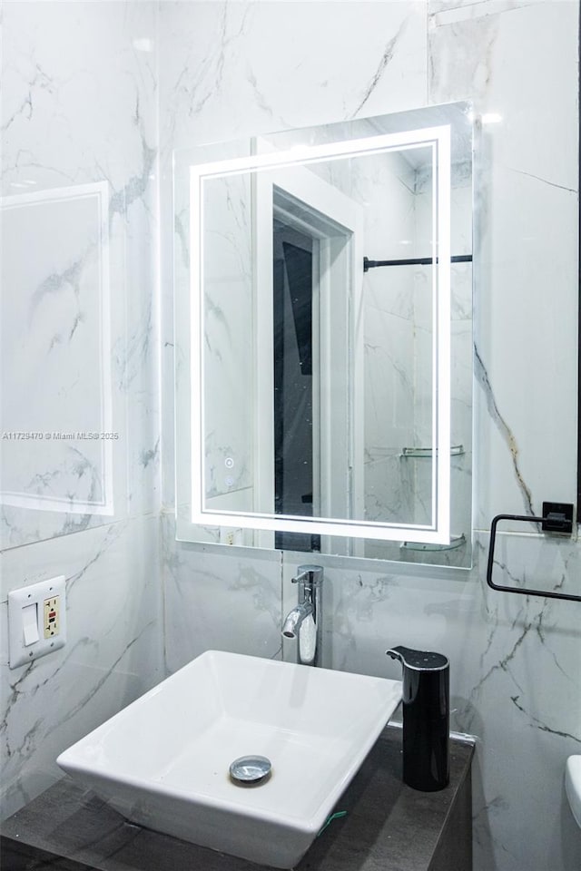 bathroom featuring sink and tile walls