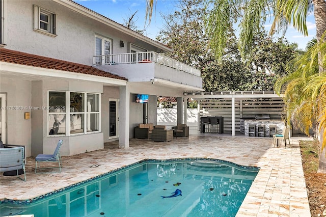 view of swimming pool featuring a bar, an outdoor living space, and a patio