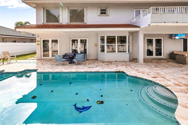 view of pool with an outdoor living space, a patio, and french doors