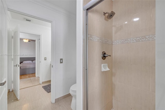 bathroom featuring toilet, tiled shower, tile patterned flooring, and crown molding