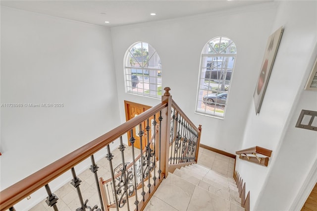 stairs with crown molding, a healthy amount of sunlight, and tile patterned floors