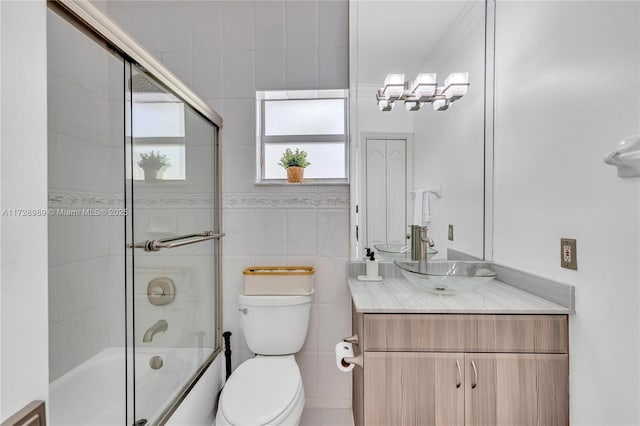 full bathroom with vanity, shower / bath combination with glass door, tile walls, and toilet