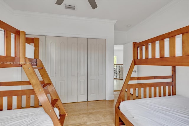 bedroom featuring ceiling fan, a closet, crown molding, and light wood-type flooring