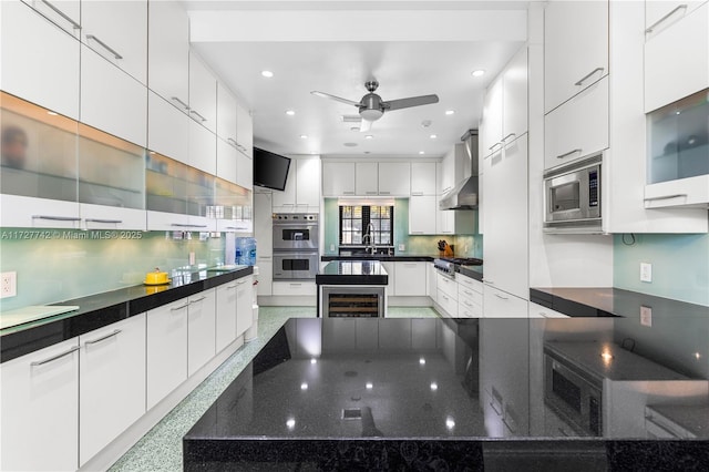 kitchen featuring white cabinets, wall chimney range hood, stainless steel appliances, wine cooler, and sink