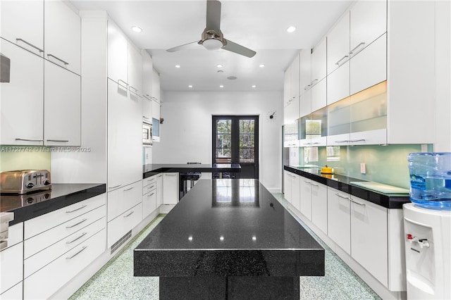 kitchen featuring stainless steel microwave, ceiling fan, french doors, backsplash, and white cabinets