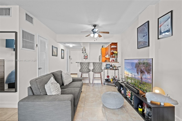 tiled living room featuring bar area and ceiling fan