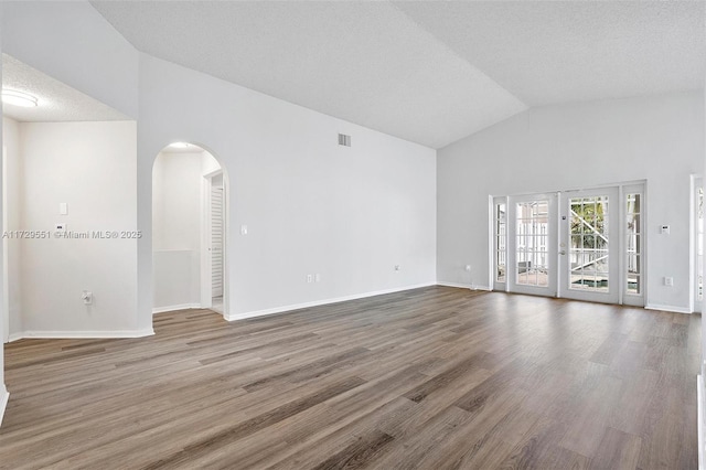 unfurnished room featuring hardwood / wood-style floors, high vaulted ceiling, and a textured ceiling