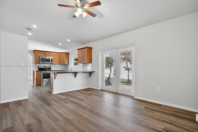 kitchen featuring a breakfast bar, tasteful backsplash, kitchen peninsula, stainless steel appliances, and french doors