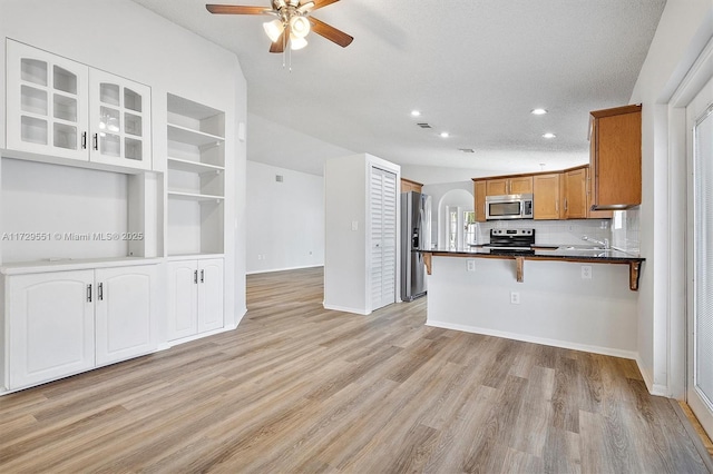 kitchen featuring sink, a breakfast bar area, stainless steel appliances, light hardwood / wood-style floors, and kitchen peninsula