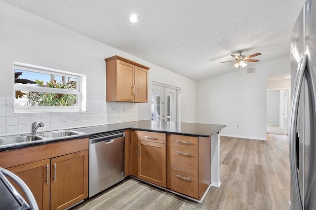 kitchen featuring sink, vaulted ceiling, kitchen peninsula, stainless steel appliances, and decorative backsplash