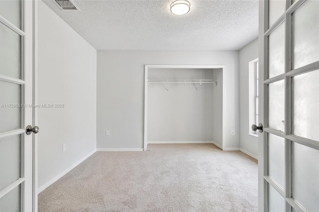 unfurnished bedroom featuring light colored carpet, a closet, and a textured ceiling