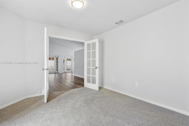 carpeted empty room featuring vaulted ceiling, a textured ceiling, and french doors