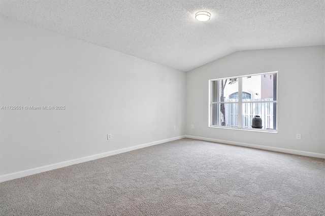 carpeted spare room with vaulted ceiling and a textured ceiling