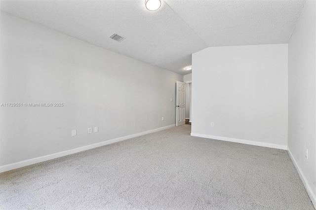 empty room with vaulted ceiling, carpet, and a textured ceiling