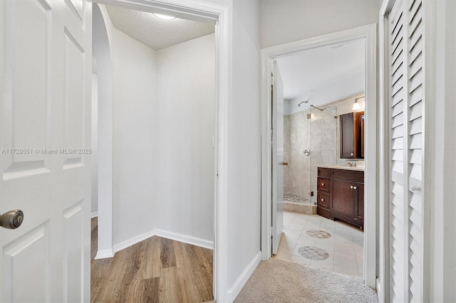 bathroom featuring vanity, a tile shower, and a textured ceiling