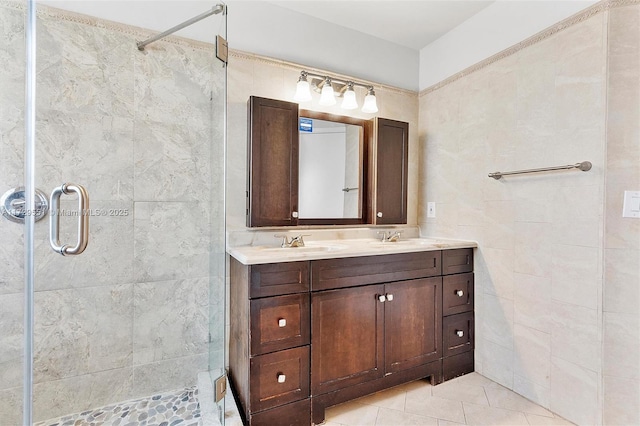 bathroom with an enclosed shower, vanity, tile patterned flooring, and tile walls