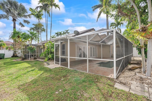 rear view of house with a lanai, a lawn, and a patio area