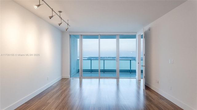 empty room with hardwood / wood-style flooring, floor to ceiling windows, and a water view