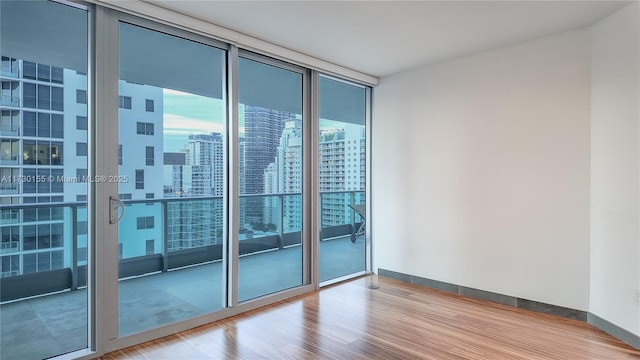 unfurnished room with a wall of windows and wood-type flooring