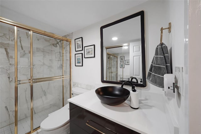 bathroom featuring a shower with door, vanity, and toilet