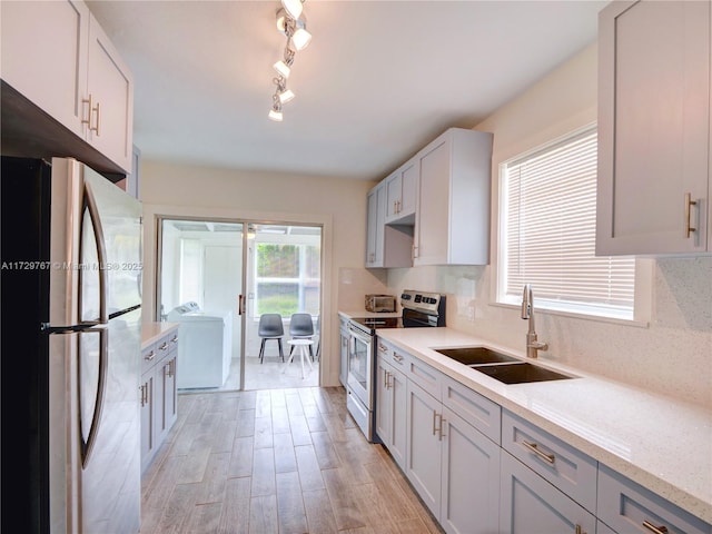 kitchen with sink, decorative backsplash, washer / dryer, and appliances with stainless steel finishes