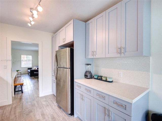 kitchen featuring stainless steel refrigerator, light hardwood / wood-style flooring, and tasteful backsplash