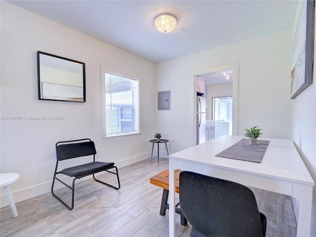 home office with washer / clothes dryer, light wood-type flooring, and electric panel