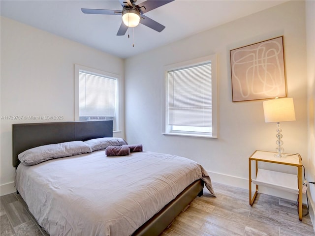 bedroom with ceiling fan, hardwood / wood-style floors, and multiple windows