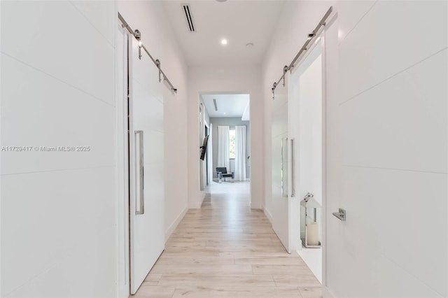 corridor featuring light hardwood / wood-style floors and a barn door