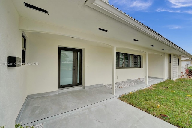 doorway to property featuring a patio and a yard