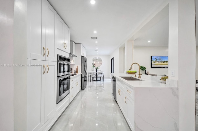 kitchen with light stone counters, sink, and white cabinetry