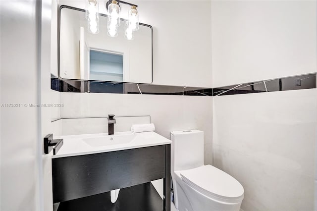 bathroom with vanity, tile walls, and toilet