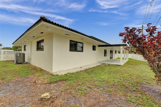 back of property with a lawn, central air condition unit, and a patio area